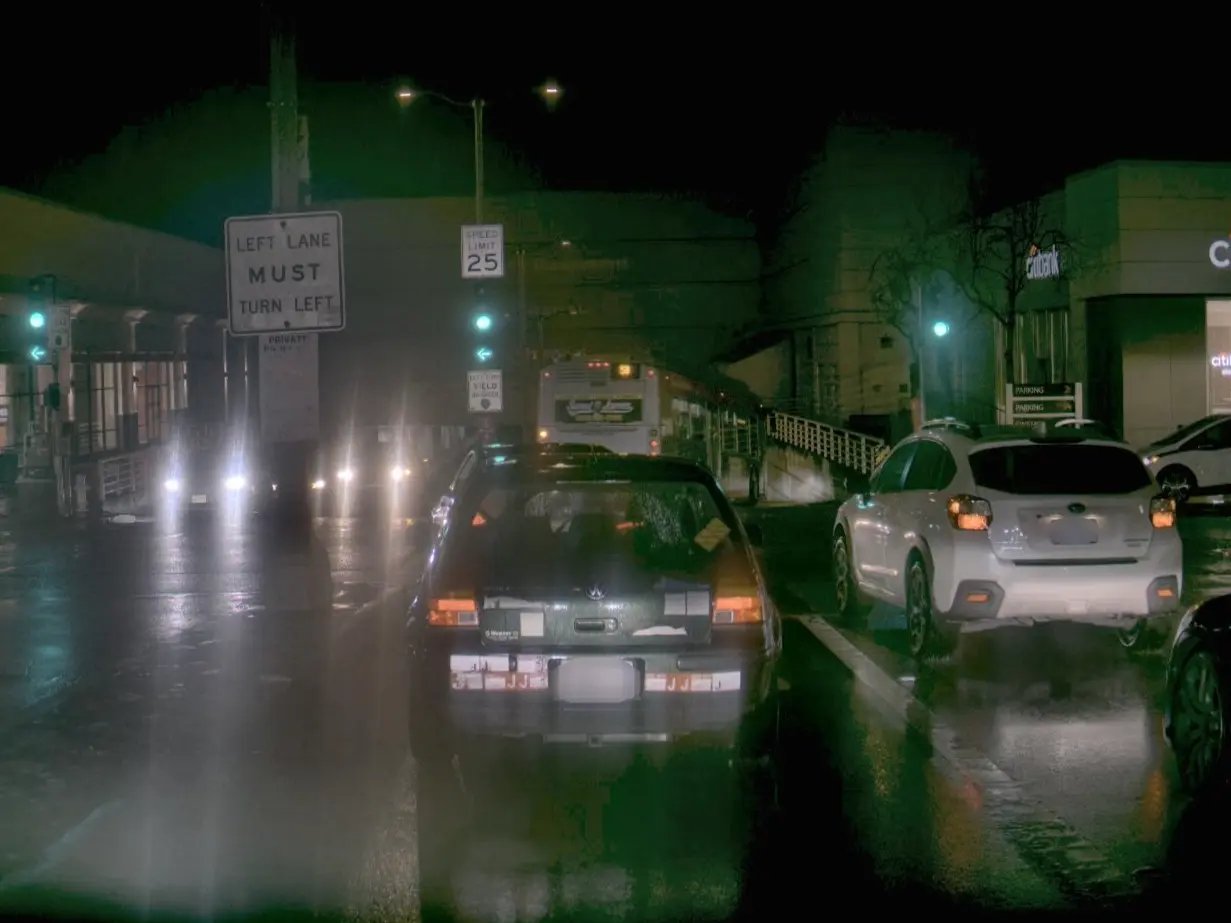 A picture of a dark street scene with a sign that says "left lane must turn left"